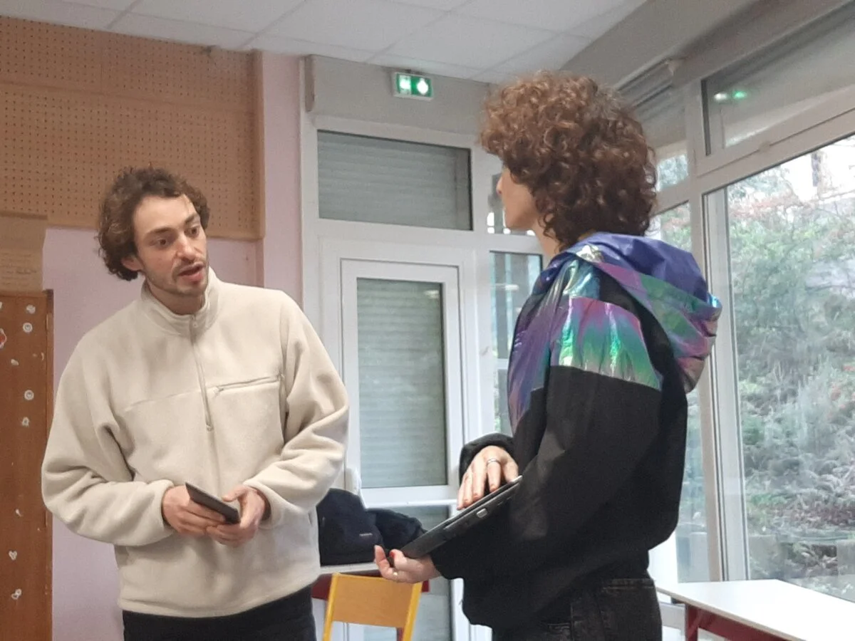 Samy et Béatrice dans une salle de classe, tableau "Les écrans pas tout le temps" au fond