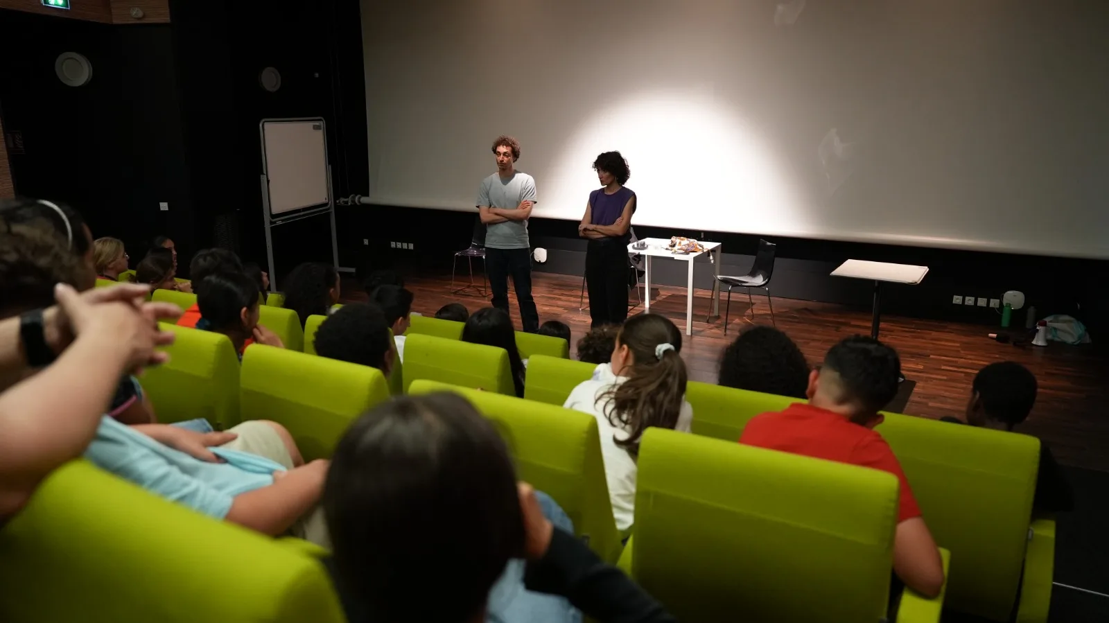 Vue d'ensemble de la salle avec public d'enfants, Samy et Béatrice sur scène en fond